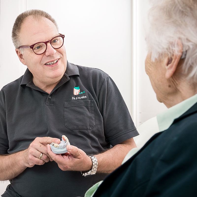 Dr. Krebs erklärt einer Patientin Zahnersatz